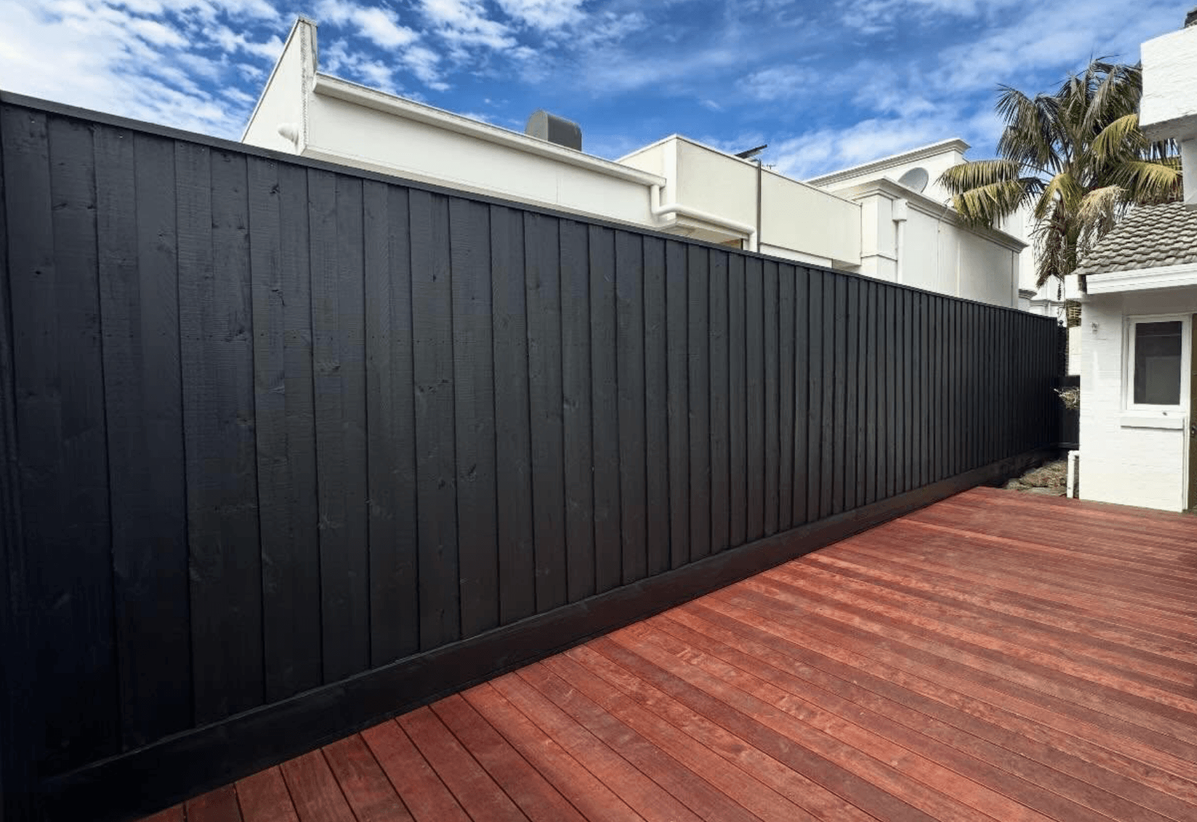 Black painted timber paling fence beside a timber deck in Harkaway, by Northern Star Painting