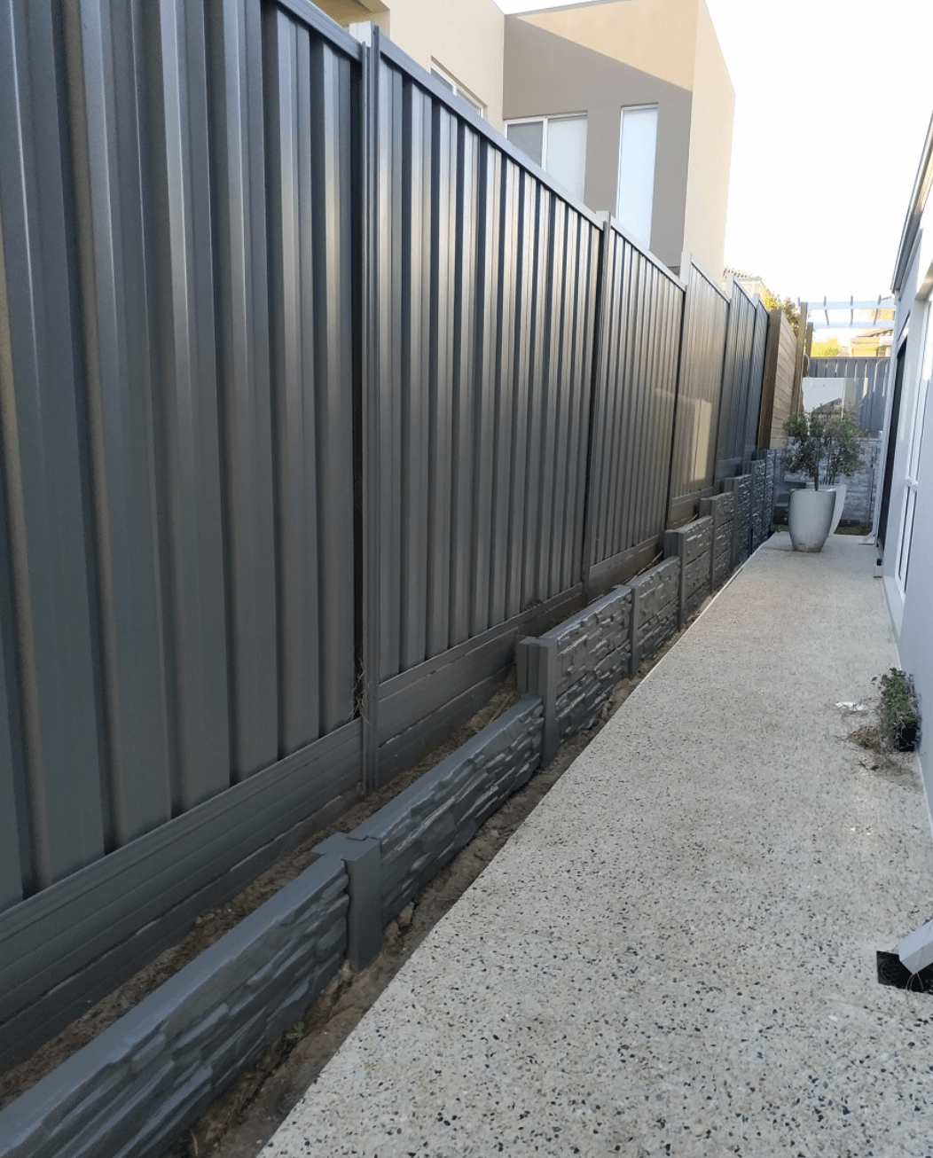Grey Colorbond side fence with painted stone-look plinth along a Narre Warren side path, by Northern Star Painting