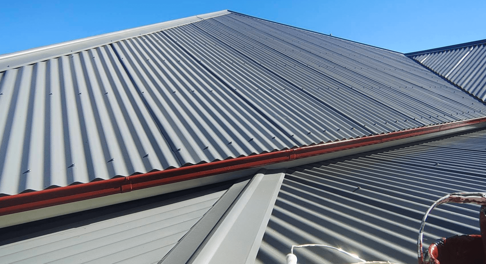 Corrugated metal roof repainted in grey with red gutters in Narre Warren North, by Northern Star Painting