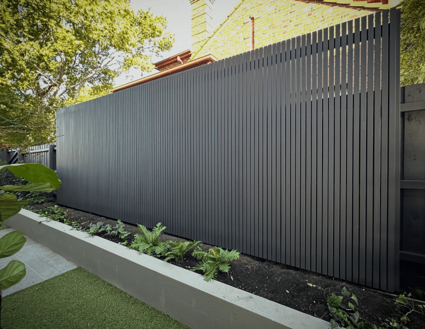 Charcoal painted vertical slat fence above a rendered garden bed in Harkaway, by Northern Star Painting