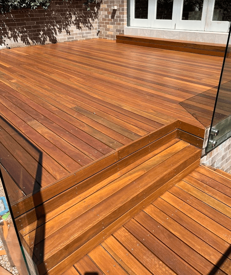 Freshly oiled hardwood deck and steps with glass pool fencing at a home in Harkaway